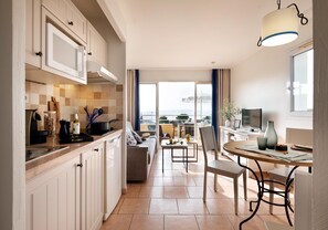A modern kitchen with a dining area, a sofa, and a view of the sea. - Stunning 4-person Sea View Haven (Roquebrune-sur-Argens)