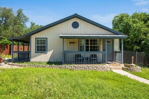 Einbungalow mit Veranda, kleinem Vorgarten und Holzzaun.
