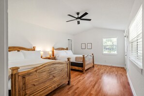 Ein Schlafzimmer mit zwei Holzbett, einem Deckenventilator, einem Fenster mit Jalousien und einem Nachttisch mit Lampe.