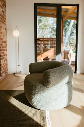 A modern living room with a textured sofa, a floor lamp, and a view through a glass door to an outdoor area.