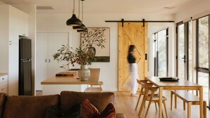 Una cocina moderna con una puerta corredera de madera, un comedor con mobiliario de madera y un ventanal que proporciona luz natural.