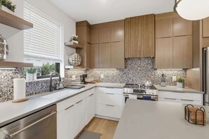 Eine moderne Küche mit Holzausstattung, einer Granit-Spritzschutzleiste, einer Edelstahl-Spüle und einem eingebauten Backofen.