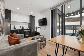 A modern apartment with a kitchen, dining area, and a large window. - CBD Retreat Studio Nearby Skytower Pool Gym Sauna (Auckland CBD)