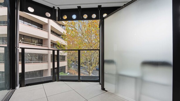 Interior moderno com varanda, janelas amplas e vista para uma árvore.
