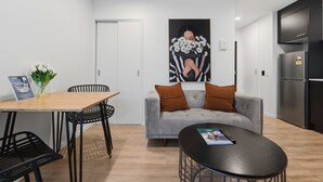 Um espaço de estar moderno com uma mesa de jantar, cadeiras, um sofá e uma área de cozinha.