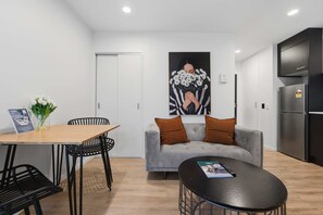 Ein modernes Wohnzimmer mit Esstisch, Stühlen, einer Couch und Küchenzeile.