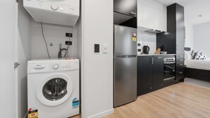 Uma cozinha compacta equipada com máquina de lavar integrada, frigorífico e micro-ondas.