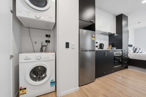 Eine kleine Küche mit Einbauwaschmaschine, Kühlschrank und Mikrowelle.