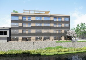 A multi-story building with a stone facade, large windows, and a rooftop garden. - Honjin Hiranoya Omeiso (Takayama)