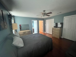 Ein Schlafzimmer mit Bett, Kommode, Fernseher und Deckenventilator.