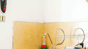 A kitchen with a sink, faucet, dish rack, and a gas stove.