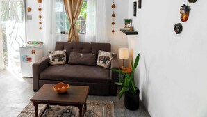 A living room with a sofa, a table, a potted plant, and wall decorations.