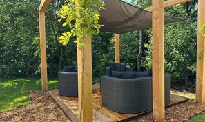 A wooden pergola with two wicker sofas and a hanging plant. - Chalet de Blauwe Regen With Sun Terrace (Balkbrug)