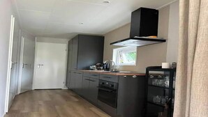 Eine kompakte Küche mit dunklen Schränken, einem Fenster und einem eingebauten Backofen.
