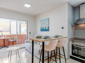 Eine moderne Küche mit Einbauofen, Essbereich mit Tisch und Stühlen sowie ein Balkon mit Aussicht.