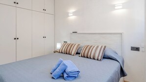 Et soveværelse med seng, puder, et natbord og et klædeskab.