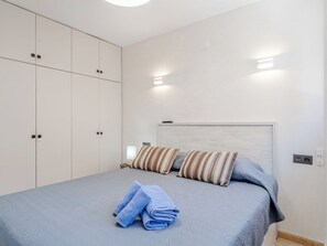 Ein Schlafzimmer mit Bett, Kissen, Nachttisch und Kleiderschrank.