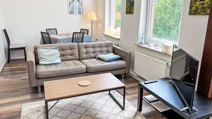 Un soggiorno con divano, tavolino, televisione e zona pranzo con sedie e tavolo.