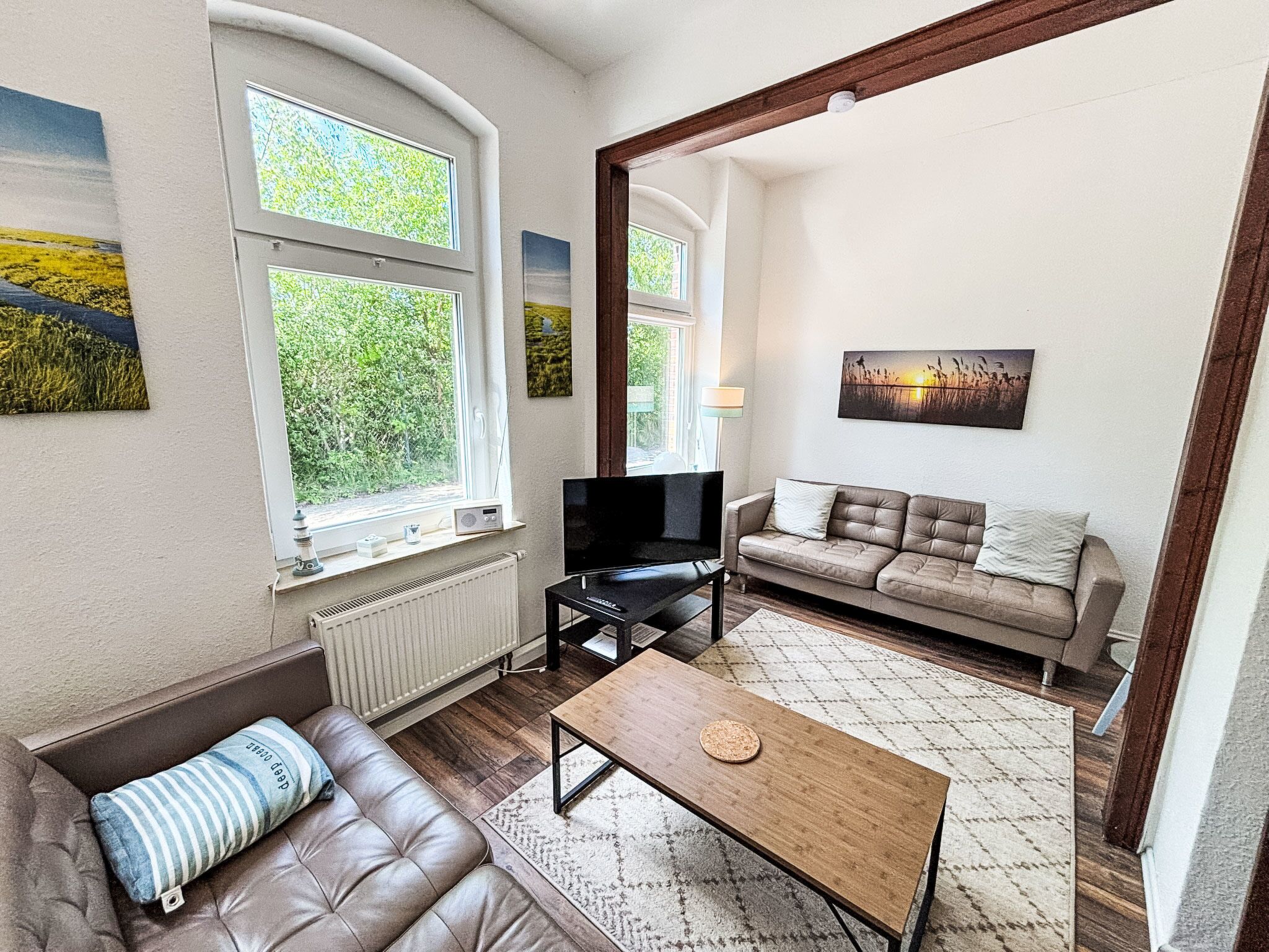 A living room with a sofa, a coffee table, a TV, and artwork on the walls.