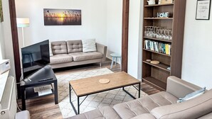 Un soggiorno con divano, tavolino, libreria e televisore.
