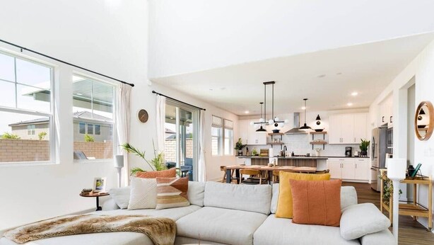 A modern living room with a sectional sofa, a round coffee table, and a dining area in the background. - Desert Oasis • Heated Pool & Spa • Sleeps 8 (Indio)