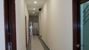 A corridor with doors on both sides, a tiled floor, and recessed lighting. - Hotel Shlyo - Taman Nusantara Prima (Gelang Patah)