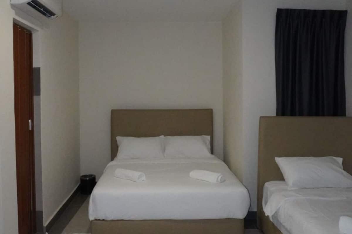 Habitación de hotel con dos camas individuales, una lámpara de techo, un equipo de aire acondicionado y una cortina oscura.
