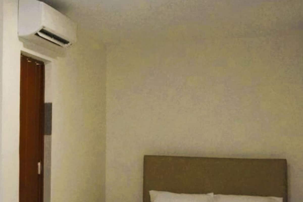Una habitación de hotel con una cama, una puerta y un equipo de aire acondicionado.