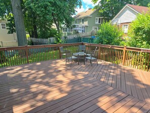 A wooden deck with a table and chairs, surrounded by a wooden railing. - Spacious 5 BD Colonial-near NYC/EWR/MetLife Stadium (Belleville)