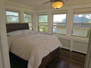 A bedroom with a bed, large windows, a ceiling fan, and a view of the outside. - Spacious 5 BD Colonial-near NYC/EWR/MetLife Stadium (Belleville)
