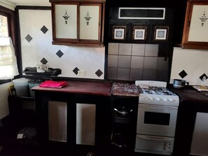 Une cuisine Ă©quipĂ©e dâune cuisiniĂšre Ă gaz, dâun four et dâun plan de travail recouvert de carreaux.