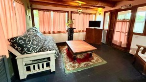 Ein gemütliches Zimmer mit einer Couch, einem Holztisch und einem Fernseher.