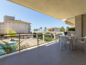 A balcony with a view of a swimming pool, a table with chairs, and a clear sky. - Costa Blanca I by Interhome (Cambrils)
