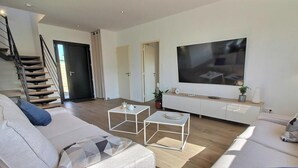 Een moderne woonkamer met een trap, een flatscreen-tv en een minimalistisch design.