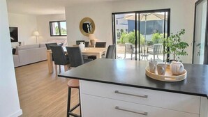 Een moderne keuken met een centraal eiland, een eetgedeelte met stoelen, een bank en een televisie.