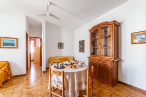 A dining area with a round table, chairs, a wooden cabinet, and a ceiling fan. - Leuca Relax&Sea n.7C, Castrignano del Capo, Italy (Castrignano del Capo)