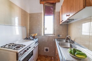 A compact kitchen with a gas stove, oven, sink, and a window with blinds. - Leuca Relax&Sea n.7C, Castrignano del Capo, Italy (Castrignano del Capo)