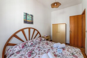 A bedroom with a wooden bed, a wardrobe, a nightstand, and a wall-mounted picture. - Leuca Relax&Sea n.7C, Castrignano del Capo, Italy (Castrignano del Capo)