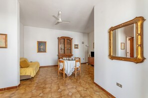 A room with a dining table, chairs, a cabinet, a bed, and a large mirror. - Leuca Relax&Sea n.7C, Castrignano del Capo, Italy (Castrignano del Capo)
