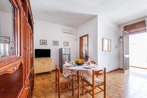 A dining area with a table set for two, a refrigerator, and a television. - Leuca Relax&Sea n.6C, Castrignano del Capo, Italy (Castrignano del Capo)