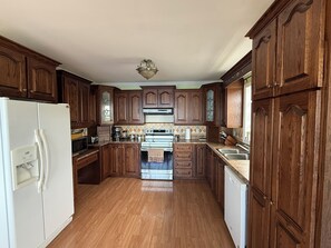A kitchen with wooden cabinets, a white refrigerator, a stove, and a dishwasher.