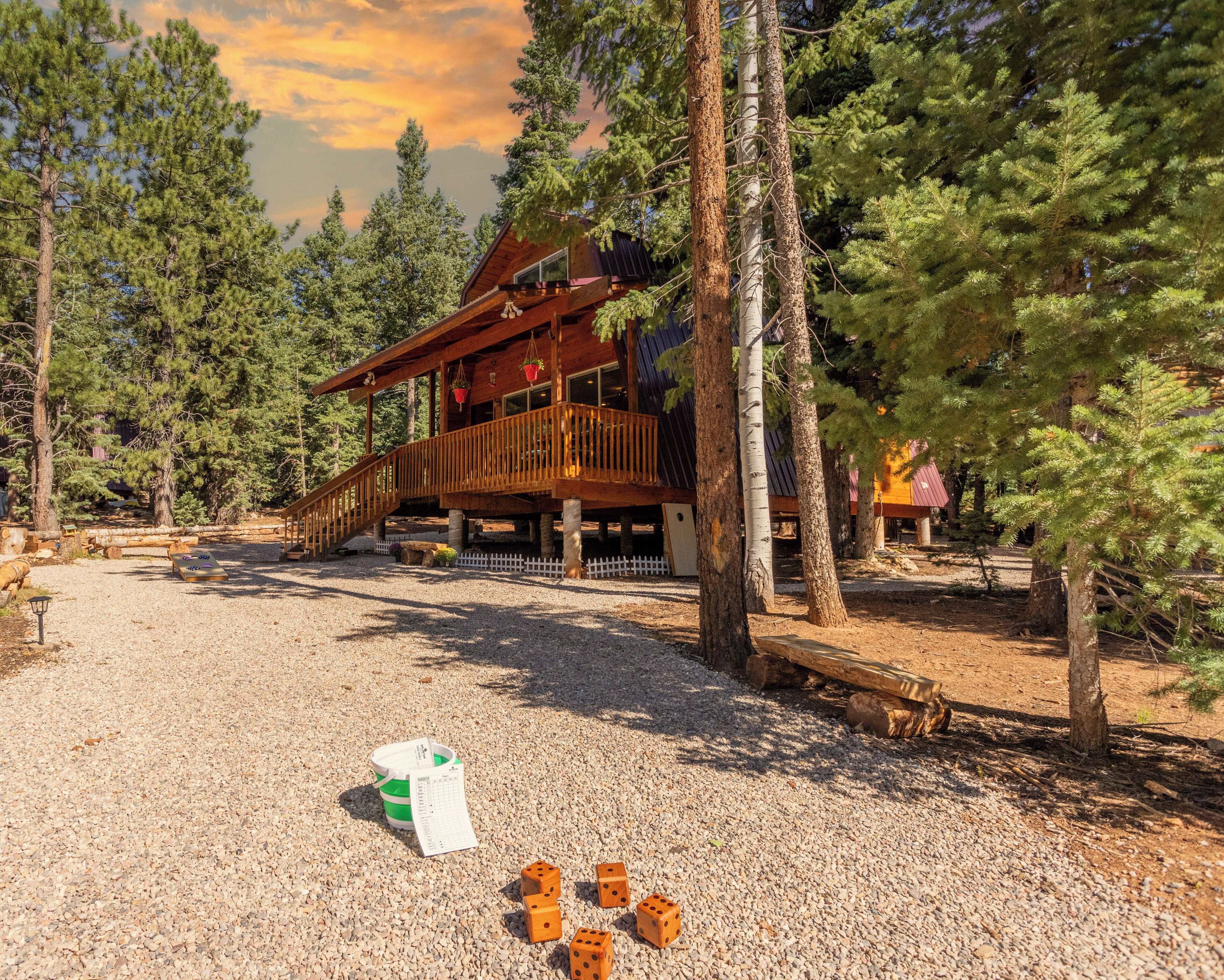 A wooden cabin with a deck, surrounded by trees.