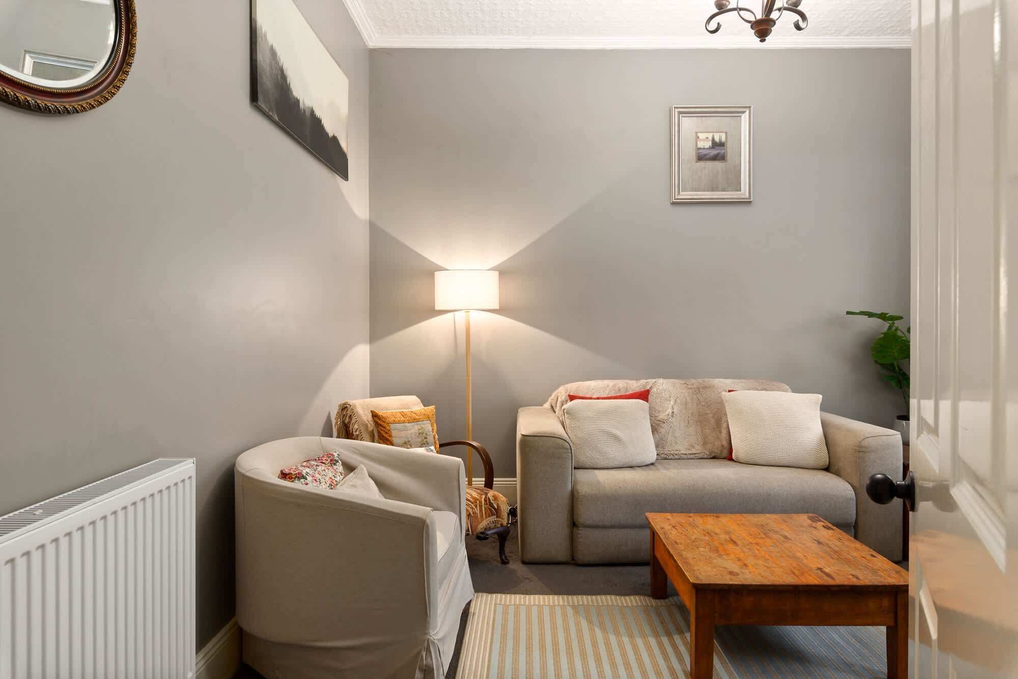 A cozy living room with a sofa, armchair, coffee table, and a floor lamp.