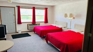 A hotel room with two beds, a desk, a chair, a TV, a window with curtains, and a lamp. - SANDS MOTEL (Boscobel)