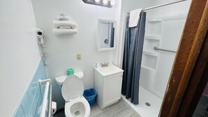 A bathroom with a toilet, sink, shower, and towel rack. - SANDS MOTEL (Boscobel)