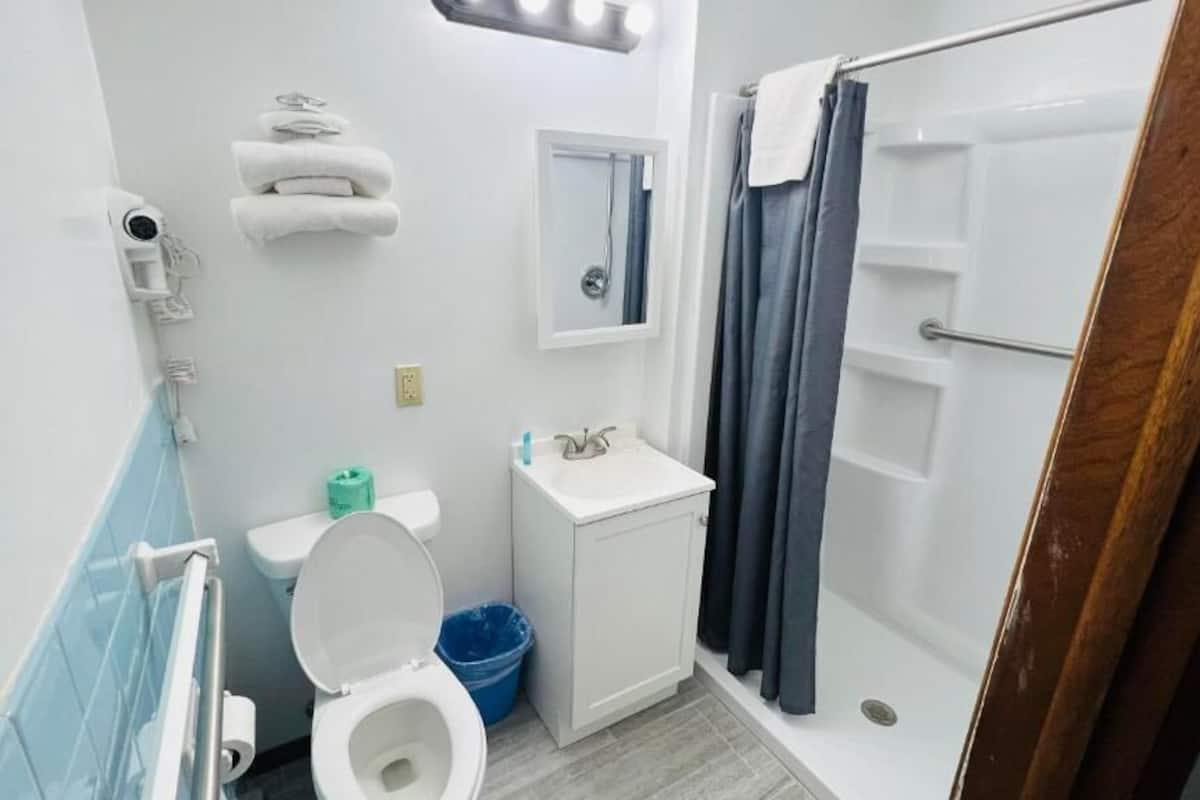 Un baño con inodoro, lavamanos, ducha y toallero.