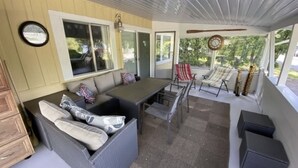 Eine überdachte Terrasse mit einer Couch, Stühlen und einem Tisch.