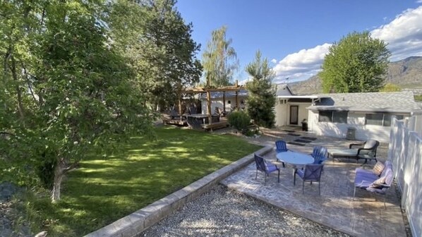 A backyard with a patio, outdoor seating, a pergola, and a house.