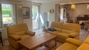 Una sala de estar con dos sofás amarillos, una mesa de centro de madera y un comedor con sillas de mimbre y una mesa.