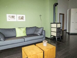 Olohuone, jossa on harmaa sohva, puinen sohvapöytä ja valkoinen kaappi.